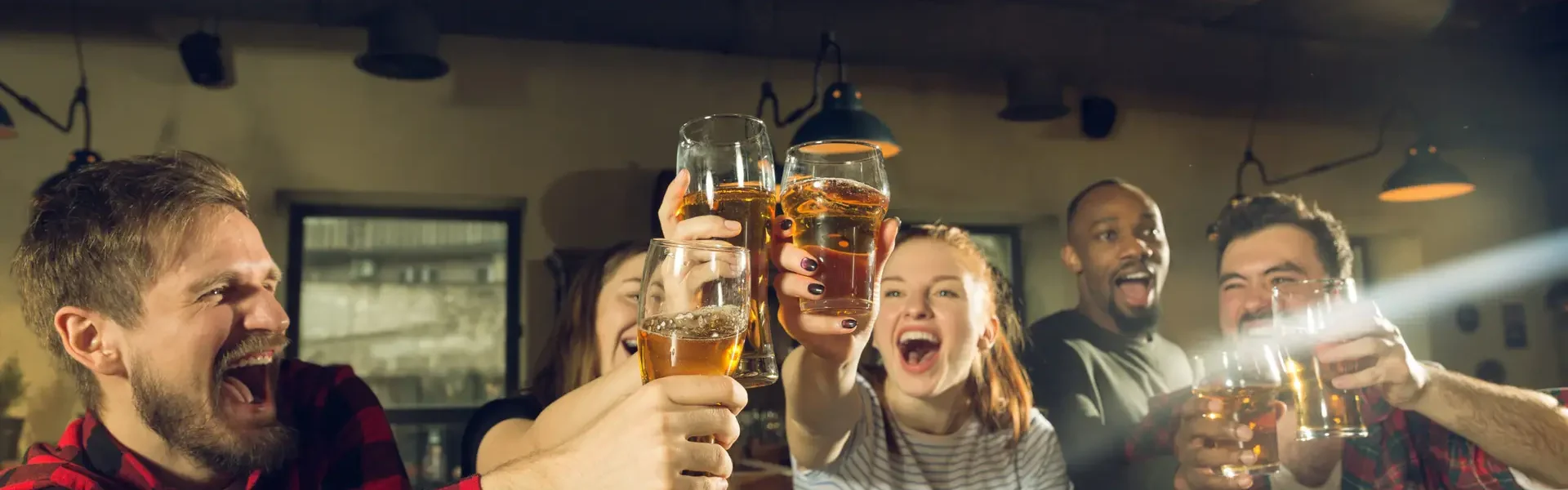 Sport fans cheering at bar, pub and drinking beer while championship, competition is going. Multiethnic group of friends excited watching translation. Human emotions, expression, supporting concept.